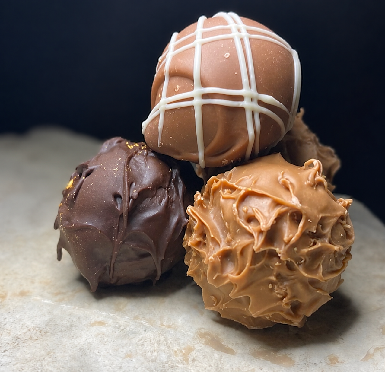 Drei klassische handgemachte Schokoladentrüffel mit unterschiedlichen Überzügen von PralinenArt